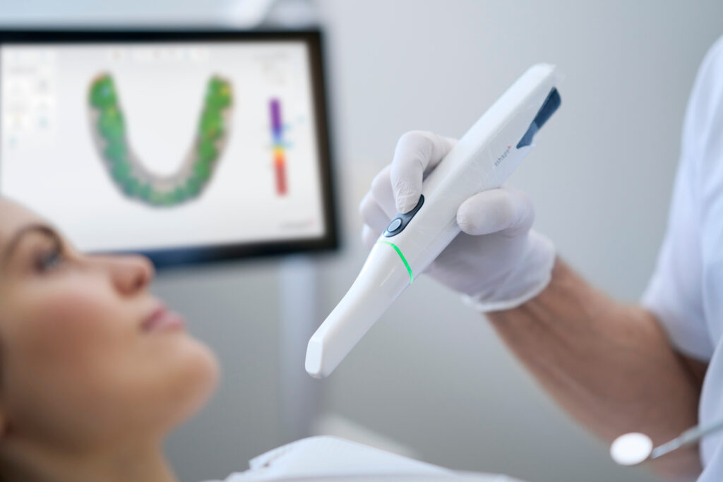 Dentist with a patient with a monitor in the background.